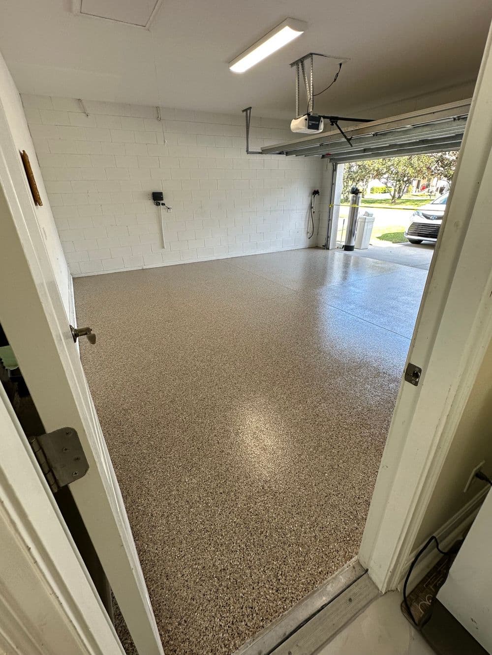 Empty garage with sleek epoxy flooring and garage door opener, well-lit and spacious.