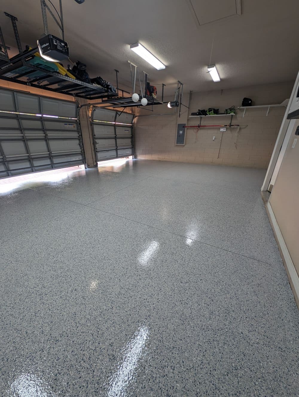 Clean and spacious garage with epoxy-coated floor and open doors, providing natural light.